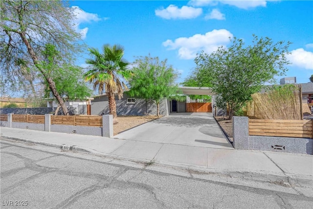 view of front of house featuring a fenced front yard, concrete driveway, and an attached carport