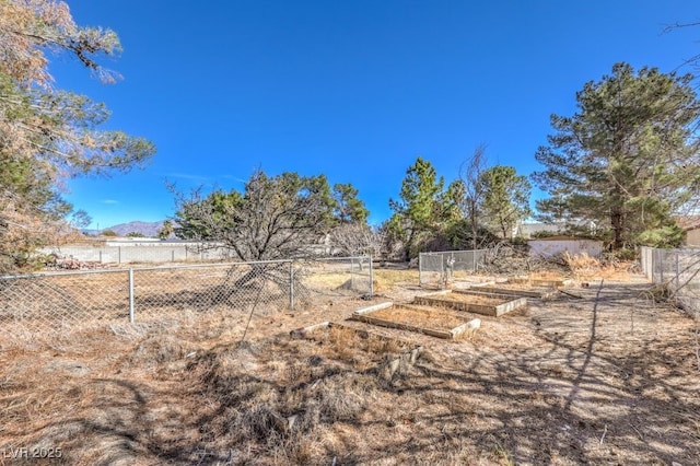 view of yard featuring fence, a mountain view, and a garden