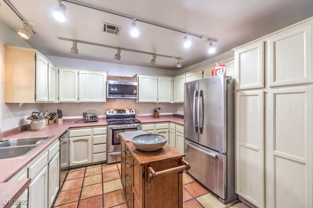 kitchen featuring a sink, stainless steel appliances, track lighting, visible vents, and light countertops