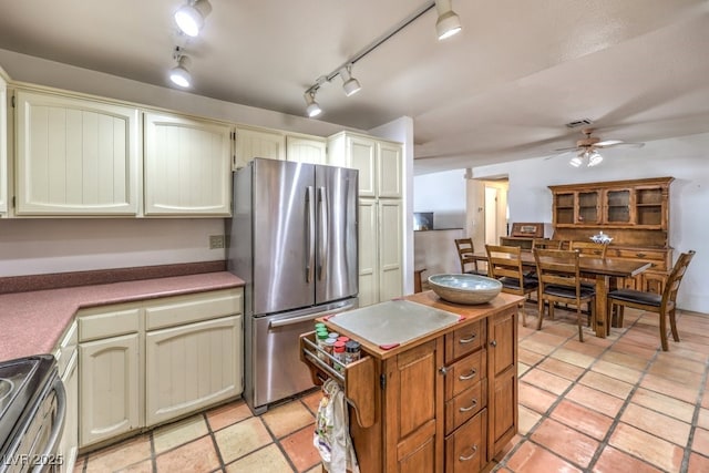 kitchen with light tile patterned flooring, a kitchen island, a ceiling fan, and appliances with stainless steel finishes