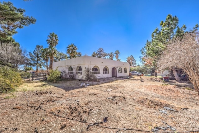 back of house featuring stucco siding and fence