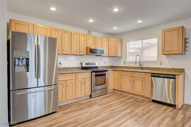 kitchen with light wood-type flooring, stainless steel appliances, light brown cabinetry, and a sink