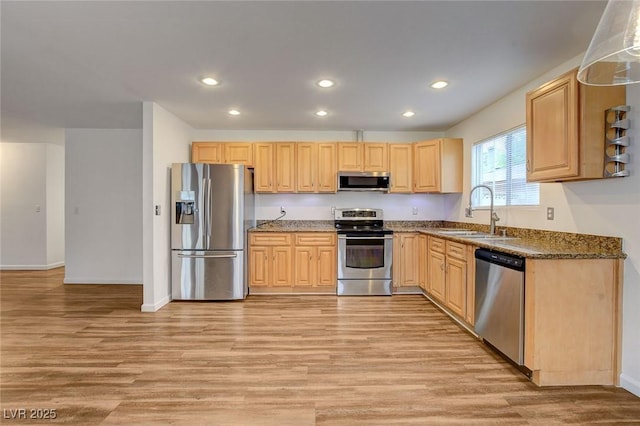 kitchen featuring appliances with stainless steel finishes, light wood-style flooring, light brown cabinets, and a sink