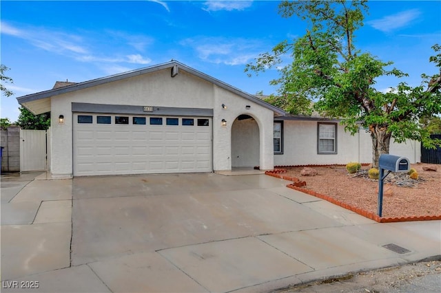 ranch-style house with fence, a garage, stucco siding, and driveway