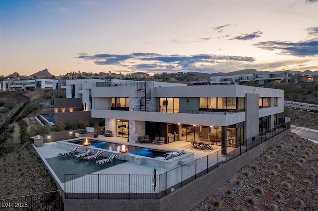 back of house with a balcony, a hot tub, a patio, a community pool, and a fenced backyard