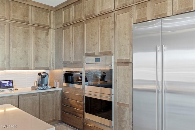 kitchen featuring stainless steel appliances, tasteful backsplash, and light countertops