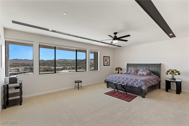 bedroom featuring baseboards, ceiling fan, a mountain view, and light colored carpet