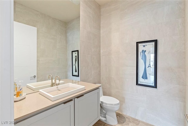 bathroom with tile walls, toilet, tile patterned flooring, and vanity