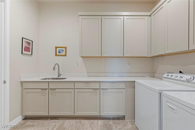 clothes washing area featuring baseboards, separate washer and dryer, cabinet space, and a sink