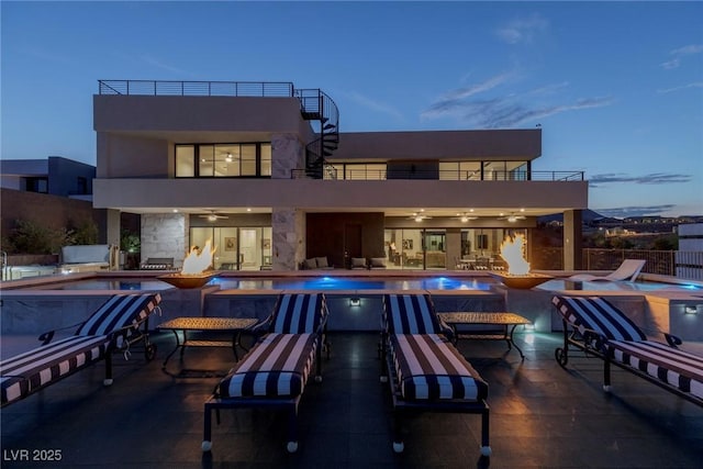 back of property with a fenced in pool, a ceiling fan, a jacuzzi, and a balcony