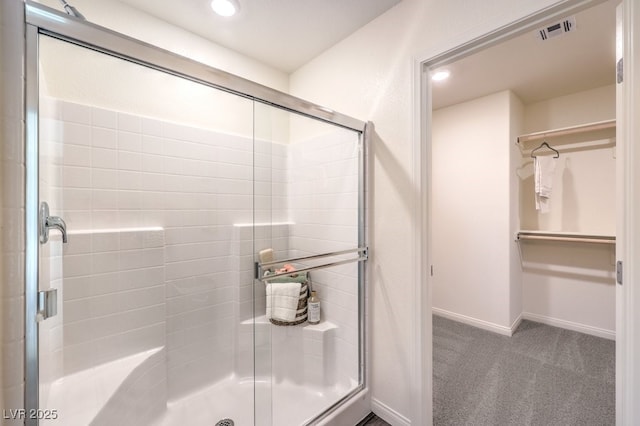 bathroom with visible vents, recessed lighting, a shower stall, a walk in closet, and baseboards