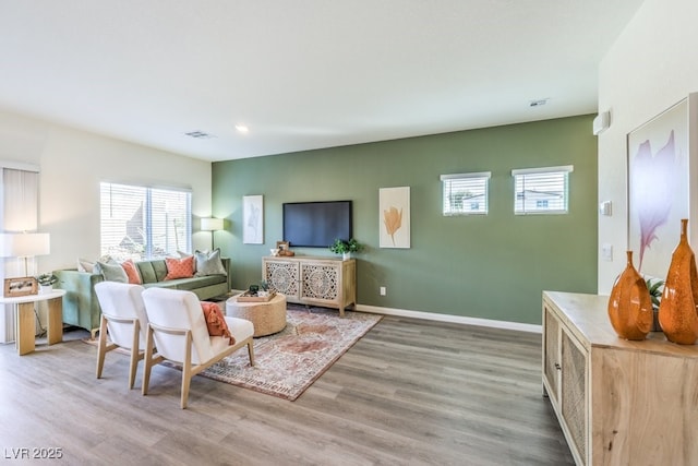 living area featuring a wealth of natural light, visible vents, and wood finished floors