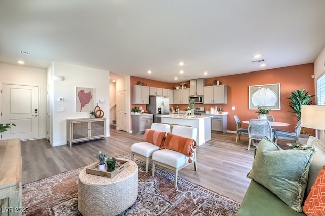 living area featuring light wood-style flooring, baseboards, and recessed lighting