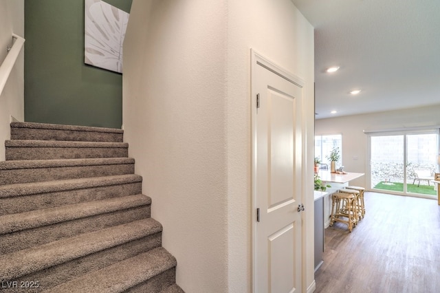 stairway with wood finished floors and recessed lighting