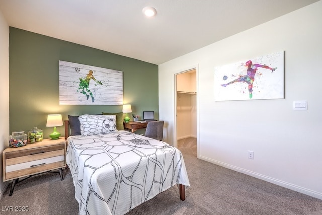 carpeted bedroom with a walk in closet and baseboards