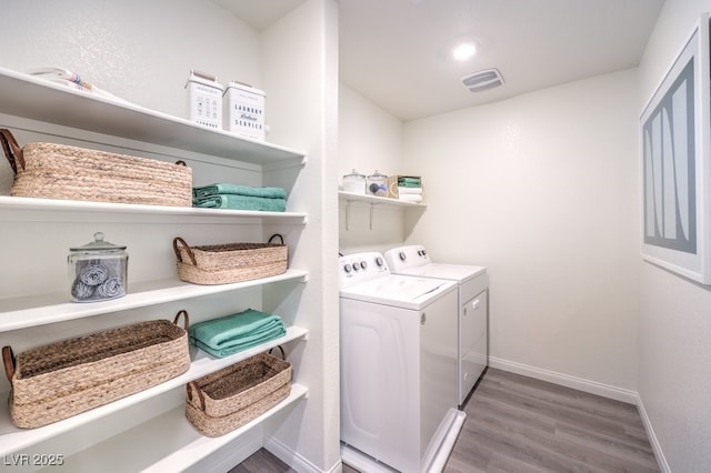 laundry area with wood finished floors, laundry area, washer and clothes dryer, visible vents, and baseboards