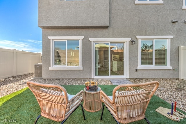back of property with stucco siding, fence, and central AC unit
