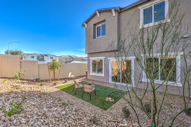 back of property featuring an outdoor fire pit, stucco siding, and fence
