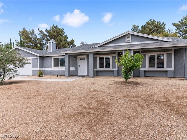 ranch-style house with an attached garage, a chimney, stucco siding, and a shingled roof