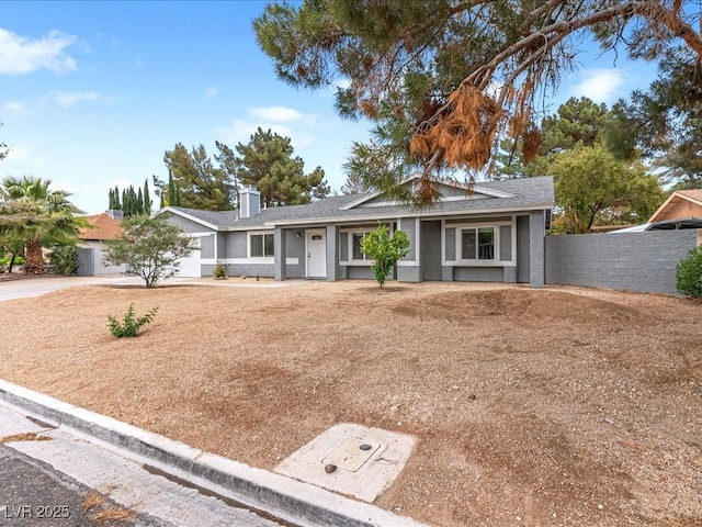 ranch-style house with roof with shingles, a chimney, fence, and driveway