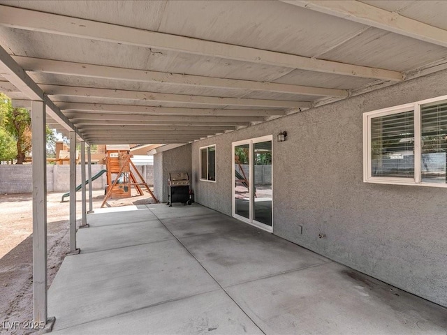 view of patio featuring a playground and fence