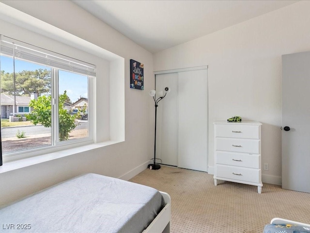 bedroom with light colored carpet, baseboards, and a closet