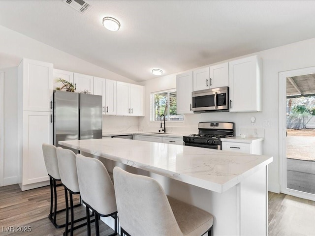 kitchen with stainless steel appliances, lofted ceiling, a kitchen bar, and healthy amount of natural light