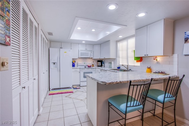 3249 Dayflower St Unit C, Las Vegas, NV 89121 - kitchen featuring a sink, a peninsula, white appliances, decorative backsplash, and white cabinets