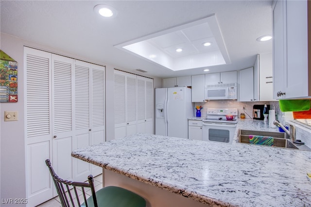 3249 Dayflower St Unit C, Las Vegas, NV 89121 - kitchen with a peninsula, a sink, a tray ceiling, white appliances, and recessed lighting