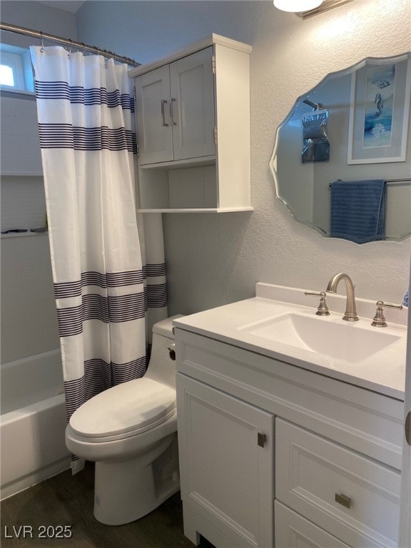 bathroom with toilet, vanity, shower / bath combo with shower curtain, and a textured wall