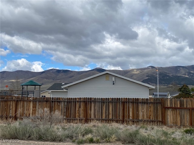 view of property exterior featuring a mountain view and fence