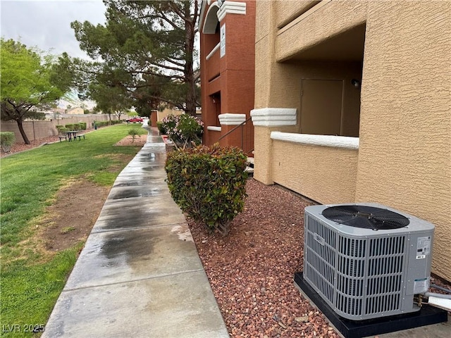 exterior space featuring a yard, fence, stucco siding, and central AC