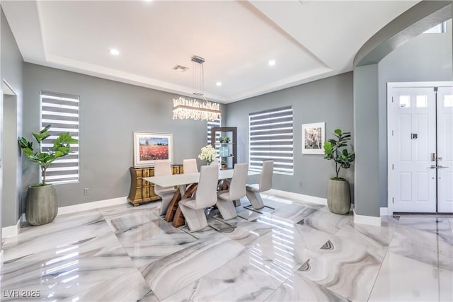 dining room with a tray ceiling, recessed lighting, a chandelier, baseboards, and light marble finish floors