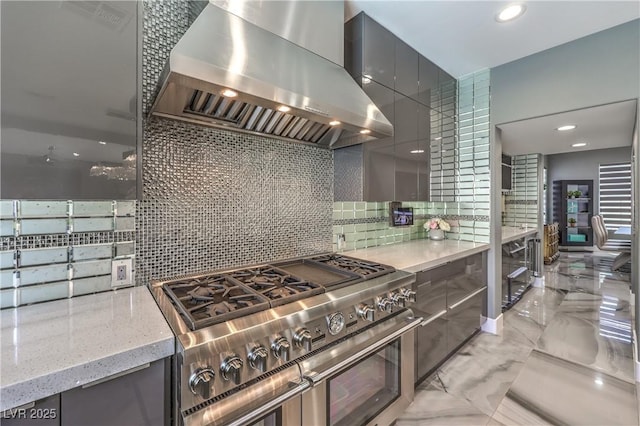 kitchen featuring gray cabinetry, range with two ovens, modern cabinets, decorative backsplash, and wall chimney range hood
