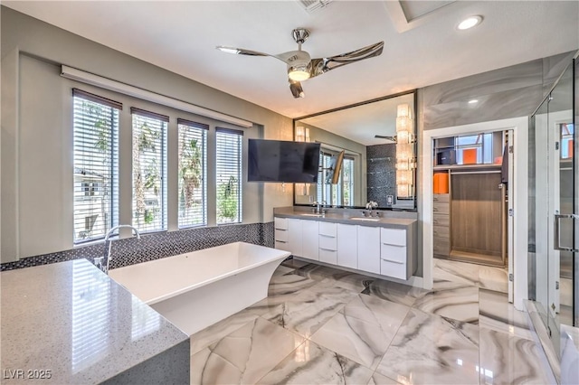 bathroom with a ceiling fan, recessed lighting, a sink, a soaking tub, and double vanity
