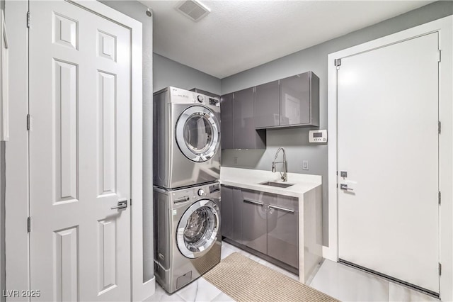 laundry room with stacked washer / drying machine, cabinet space, and light tile patterned floors