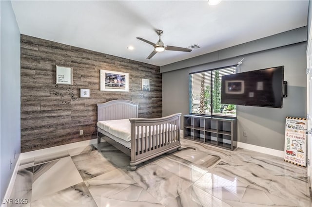 bedroom with an accent wall, baseboards, recessed lighting, wood walls, and marble tiled floors