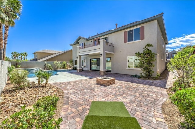 rear view of house featuring a balcony, stucco siding, a patio, and a fenced backyard