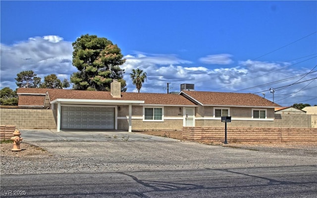 ranch-style house with a garage, fence, a chimney, stucco siding, and concrete driveway