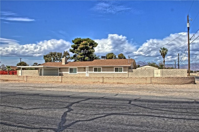 ranch-style house featuring fence, an attached garage, stucco siding, and a chimney
