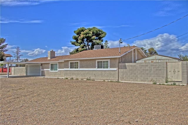 view of front of property featuring fence, a garage, stucco siding, central AC, and a chimney