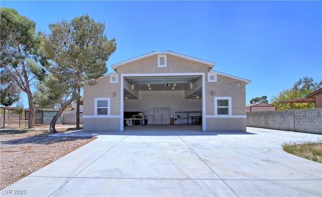rear view of property with stucco siding, fence, and a garage