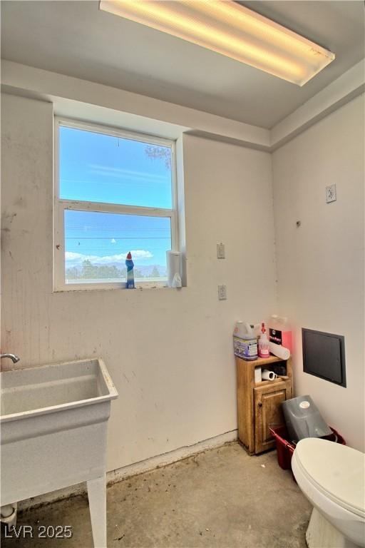 bathroom with toilet, a sink, and concrete floors