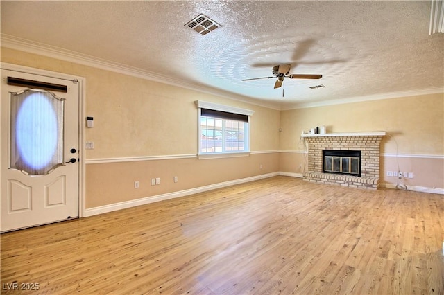 unfurnished living room with wood finished floors, a textured ceiling, ceiling fan, a brick fireplace, and ornamental molding