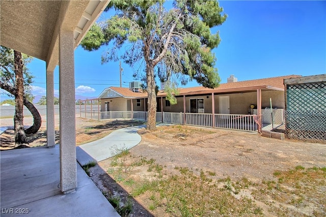 view of front of home featuring a chimney, fence, and a patio area