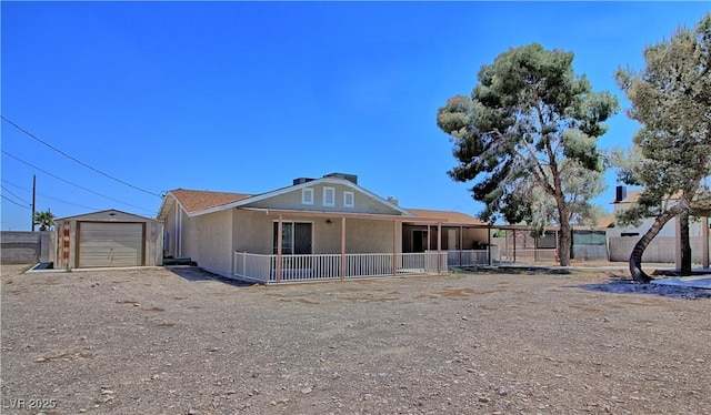back of property with an outdoor structure, fence, stucco siding, and a garage
