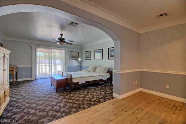 living room with arched walkways, a ceiling fan, baseboards, crown molding, and wood finished floors