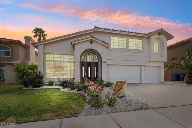 mediterranean / spanish-style home featuring an attached garage, concrete driveway, stucco siding, a tiled roof, and a lawn