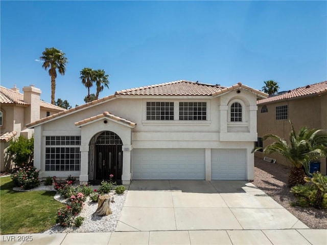 mediterranean / spanish home with concrete driveway, a garage, stucco siding, and a tiled roof