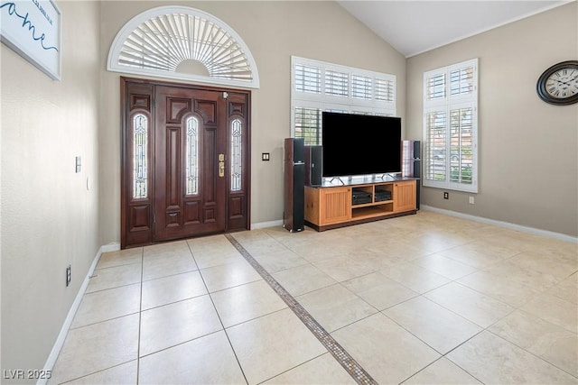 foyer featuring baseboards, light tile patterned floors, and high vaulted ceiling